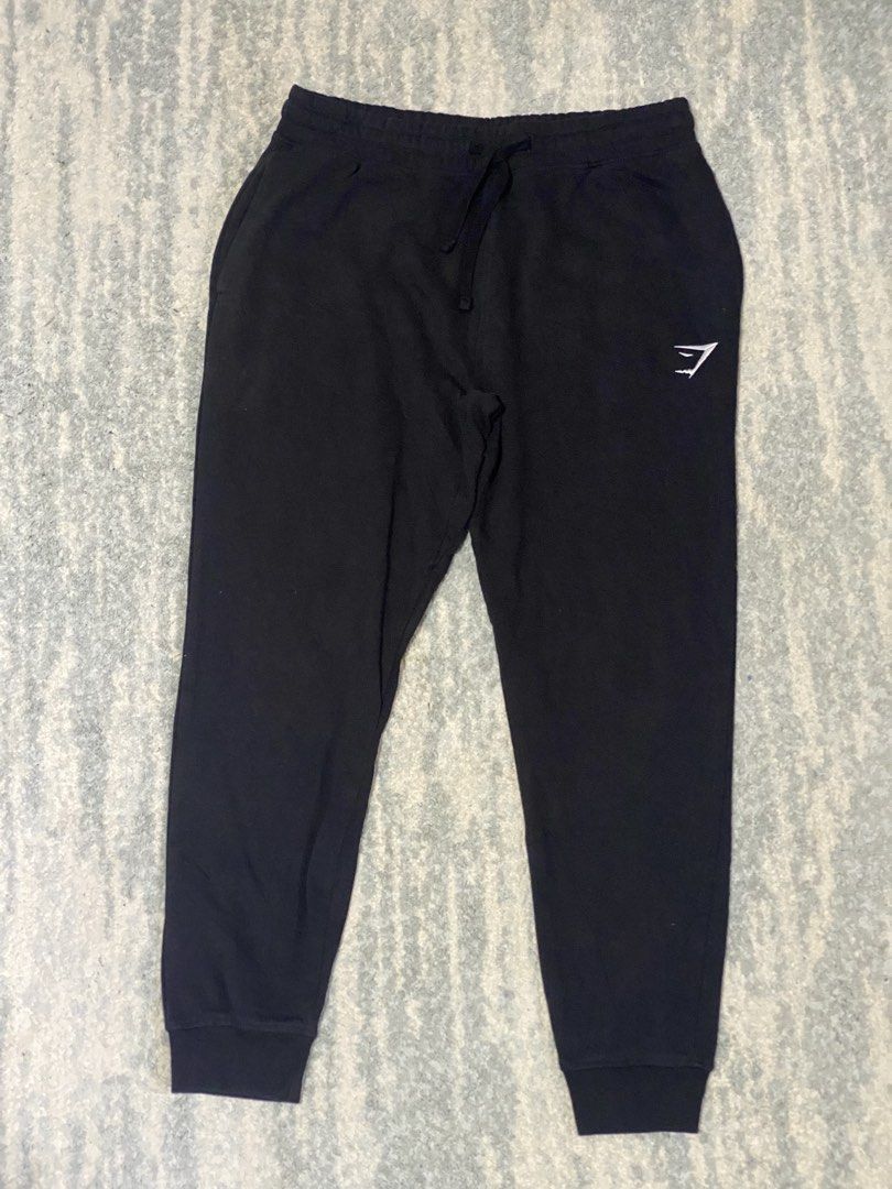 Gymshark Black Sweatpants Joggers Size M (Category: Joggers) located in Manila. Submitted by kuya_moto (Listing ID 1470827646, Image 1). Description: - Brand: Gymshark - Color: Black - Size: Medium - Material: 80% Cotton, 20% Polyester - Origin: Made in Bangladesh - Features: Soft fabric, elastic waistband with adjustable drawstring, embroidered white logo on the left leg, and ribbed ankle cuffs - Condition: Great for workouts or casual wear.