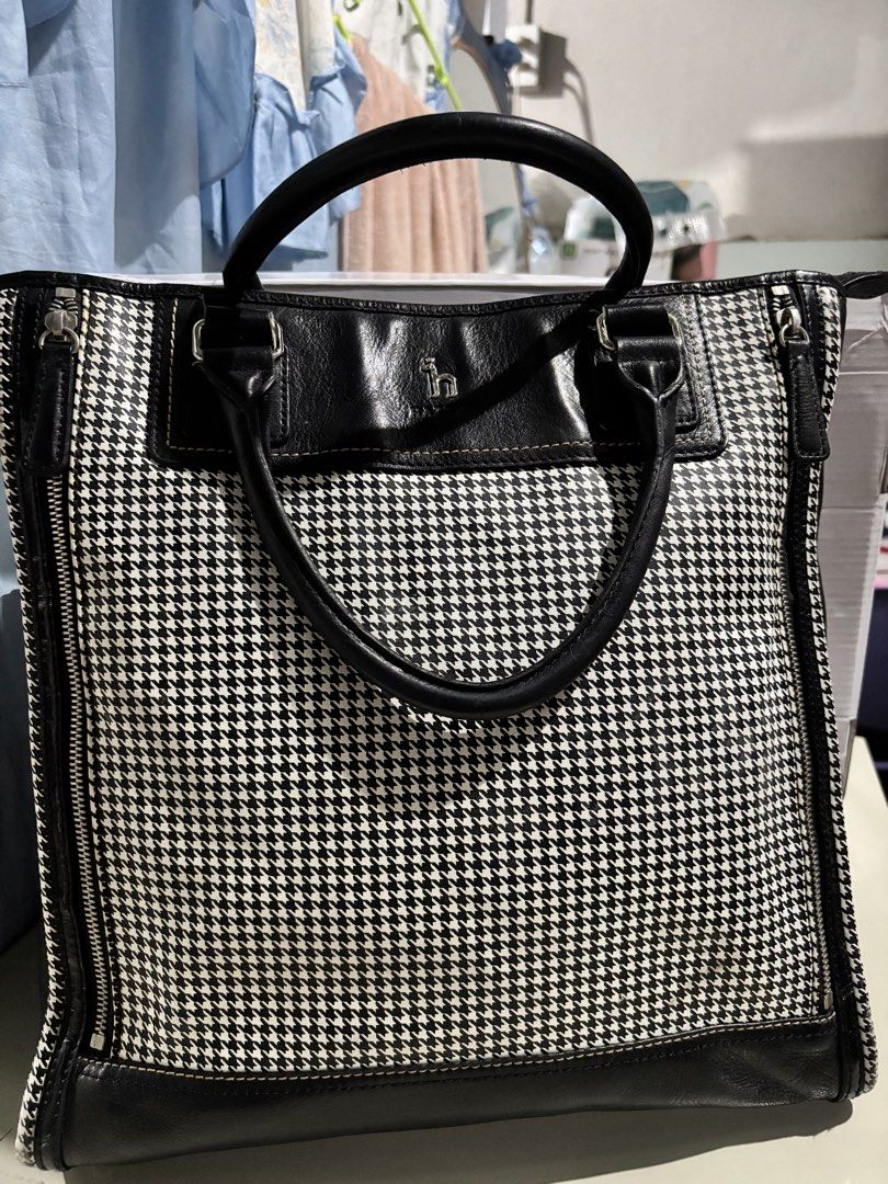 HAZZYS Black and White Houndstooth Tote Bag (Category: Tote Bags) located in Rizal. Submitted by va_nes_sa_ (Listing ID 1470819949, Image 1). Description: - Brand: HAZZYS - Design: Classic black and white houndstooth pattern with black leather trim - Handles & Strap: Dual top handles plus a detachable branded shoulder guitar strap with metal hardware - Protection: Metal feet on the bottom base for durability - Expandability: Convenient zipper exp