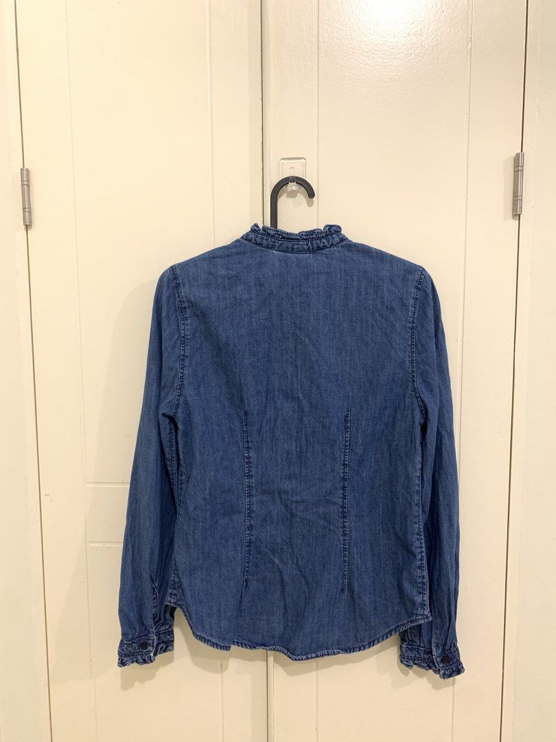 H&M Denim Ruffle Neck Blouse Size XS (Category: Blouses) located in Pasig City. Submitted by lovedbyri (Listing ID 1470861710, Image 3). Description: - Brand: H&M - Item: Denim button-down shirt - Color: Blue - Size: XS - Fit: Slim fit through the body - Details: Ruffled collar and ruffled long-sleeve cuffs, front button closure - Condition: Clean, no stains or damage spotted - Styling: Great with jeans or skirts for a casual look.