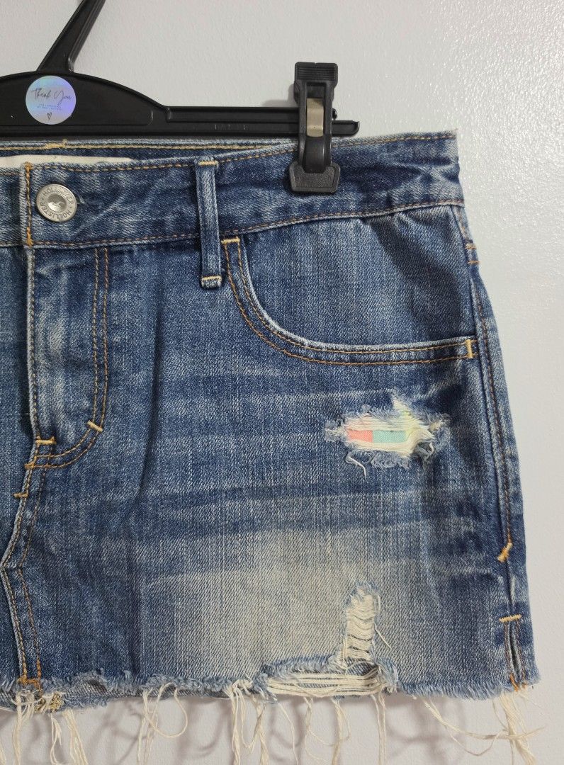 Hollister Distressed Denim micro Skirt with Rainbow Patch (Category: Skirts) located in Paranaque City. Submitted by franinnashop (Listing ID 1470795991, Image 2). Description: Declutter - Brand: Hollister - Style: Denim skirt in medium blue wash - Size: Waist 32-33 inches, length 11 inches - Details: Distressed with frayed hem, unique multi-colored patch under front rip - Pockets: Classic 5-pocket style with signature seagull logo on coin pocket
