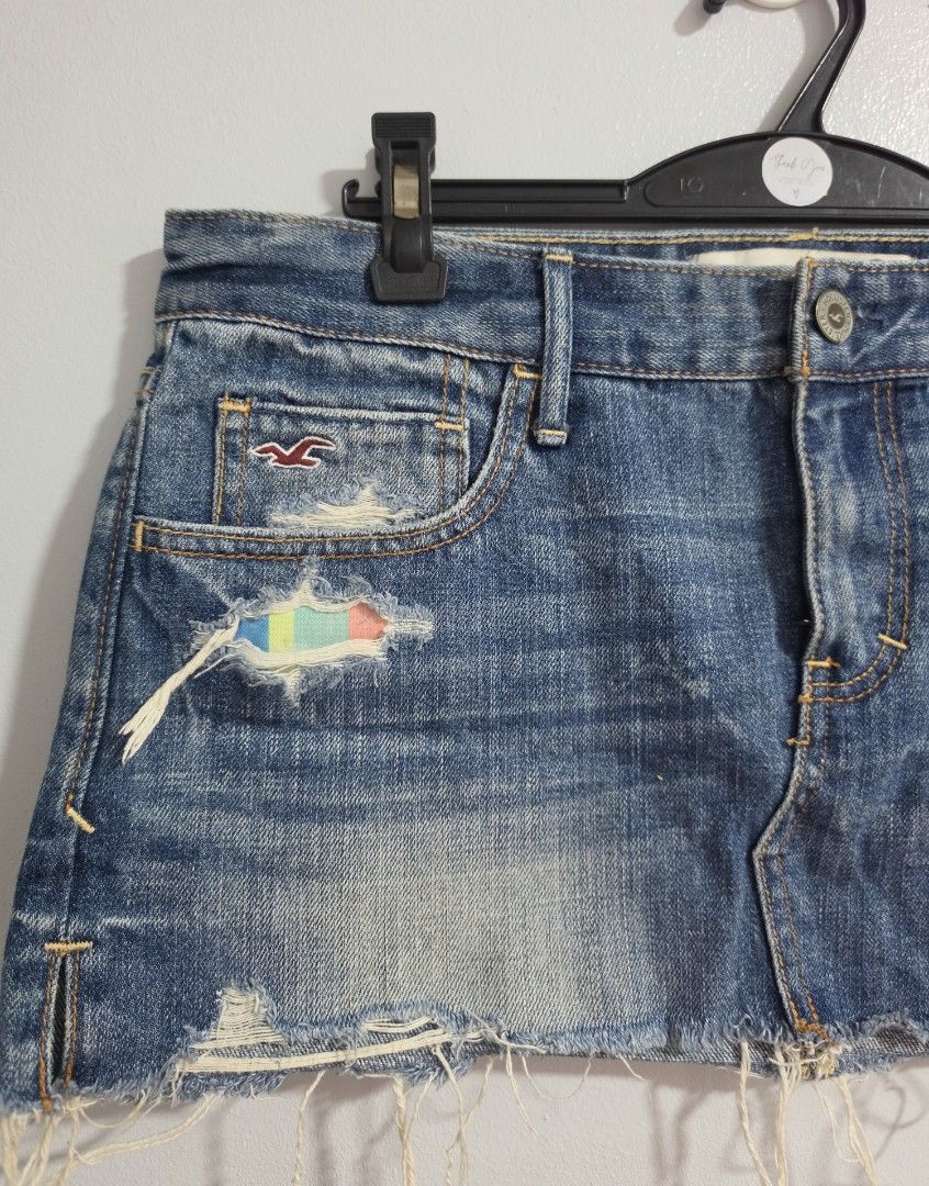 Hollister Distressed Denim micro Skirt with Rainbow Patch (Category: Skirts) located in Paranaque City. Submitted by franinnashop (Listing ID 1470795991, Image 3). Description: Declutter - Brand: Hollister - Style: Denim skirt in medium blue wash - Size: Waist 32-33 inches, length 11 inches - Details: Distressed with frayed hem, unique multi-colored patch under front rip - Pockets: Classic 5-pocket style with signature seagull logo on coin pocket