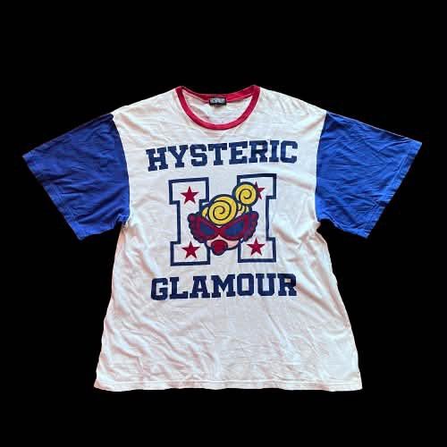 Hysteric Glamour Graphic Print Ringer Tee (Category: Tshirts & Polo Shirts ) located in Caloocan City. Submitted by landcruiser76__ (Listing ID 1470776766, Image 1). Description: Hysteric Glamour ringer t-shirt in white with bold blue sleeves and red collar trim. Large varsity letter H graphic on the front featuring the iconic blonde character and stars. Back print has the same Hysteric Glamour character artwork in red lettering. Short sleeves, r