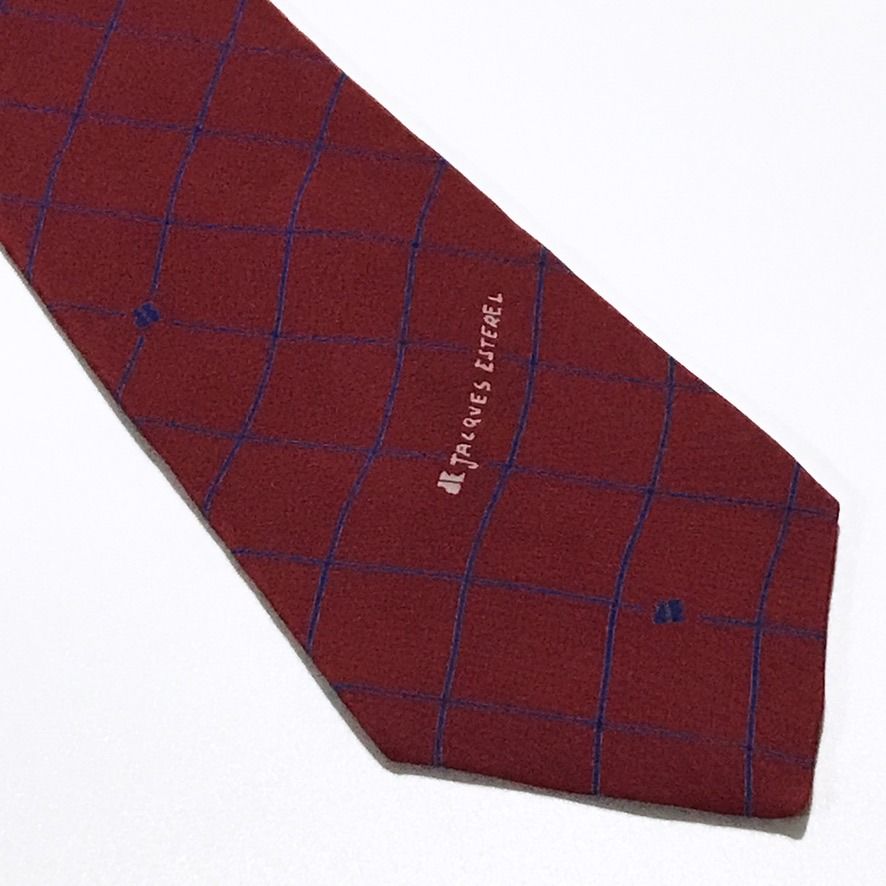 Jacques Esterel Vintage Grid Pattern Maroon Neck Tie (Category: Ties) located in Taguig. Submitted by retrogaze (Listing ID 1470762892, Image 2). Description: This vintage 100% silk necktie by Jacques Esterel features a rich maroon ground with a smooth, soft-finish twill drape. The body is styled in an open windowpane grid pattern composed of fine diagonal pinstripes in navy blue, punctuated by subtle embroidered "JE" monogram accents and a signa