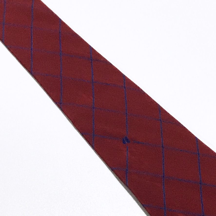 Jacques Esterel Vintage Grid Pattern Maroon Neck Tie (Category: Ties) located in Taguig. Submitted by retrogaze (Listing ID 1470762892, Image 3). Description: This vintage 100% silk necktie by Jacques Esterel features a rich maroon ground with a smooth, soft-finish twill drape. The body is styled in an open windowpane grid pattern composed of fine diagonal pinstripes in navy blue, punctuated by subtle embroidered "JE" monogram accents and a signa