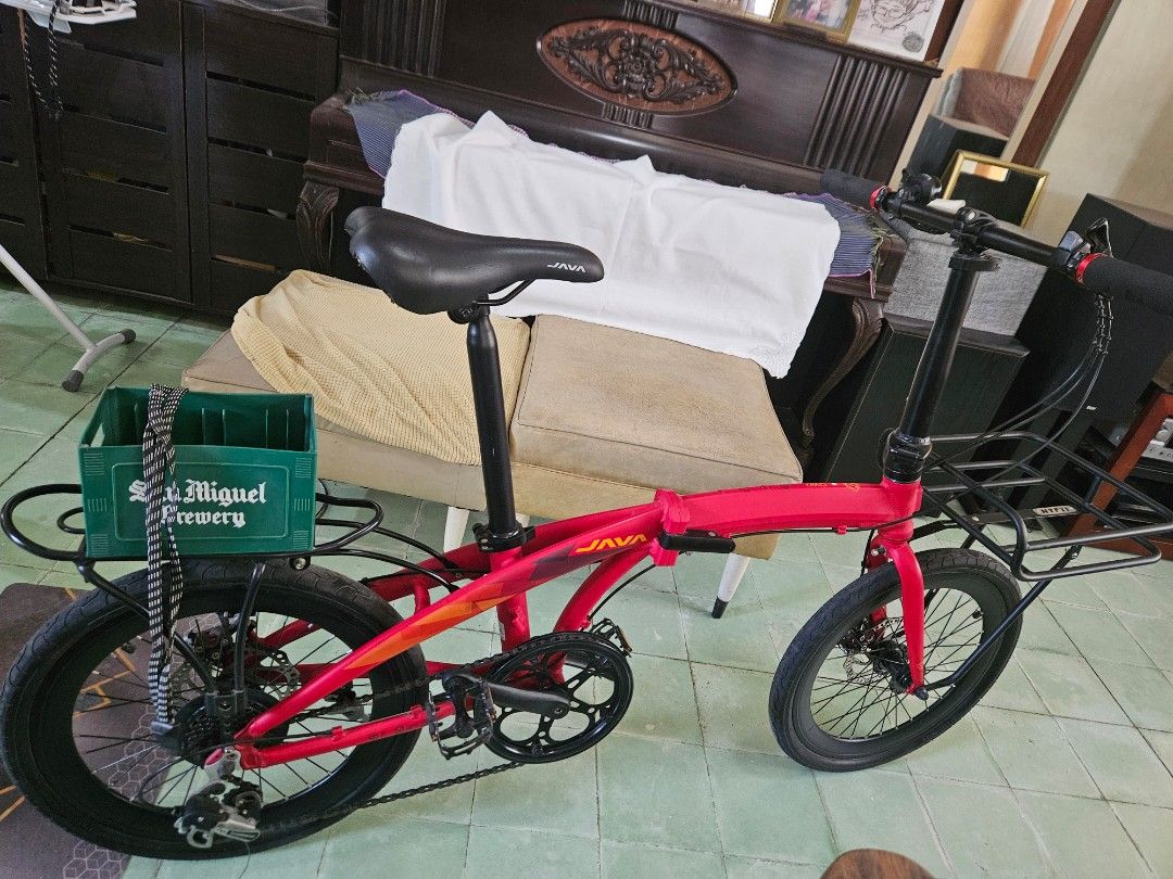 JAVA Red Folding Bicycle with Front and Rear Racks (Category: Bicycles) located in Calamba. Submitted by jingmdejes57879 (Listing ID 1470774309, Image 1). Description: - Brand/Model: Red JAVA folding bike - Setup: Equipped with a front rack and a iconic green San Miguel crate on the back - Components: Black handlebars, saddle, and wheels with reliable disc brakes - Condition: Fully functional frame folding mechanism, smooth chain/gears, with mino