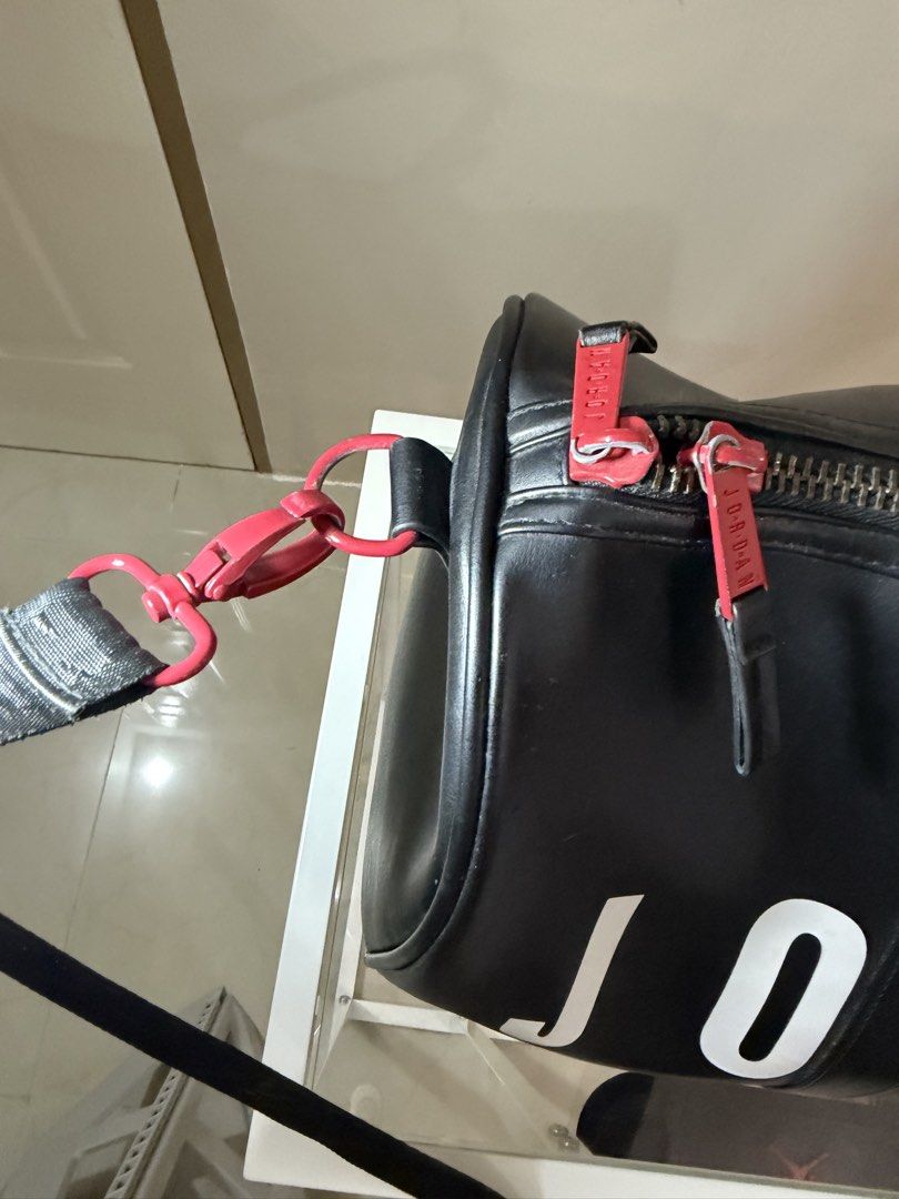 Jordan Black Duffle Bag with Red Accents (Category: Sling Bags) located in Rosario. Submitted by chippycoco (Listing ID 1470765902, Image 3). Description: - Color: Classic Black with bold White Jordan lettering - Accents: Signature Red Jumpman logo on front and shoulder strap pad - Hardware: Premium red hardware with matching Jordan-branded zipper pulls - Straps: Sturdy double carrying handles and an adjustable black shoulder strap - Condition: B