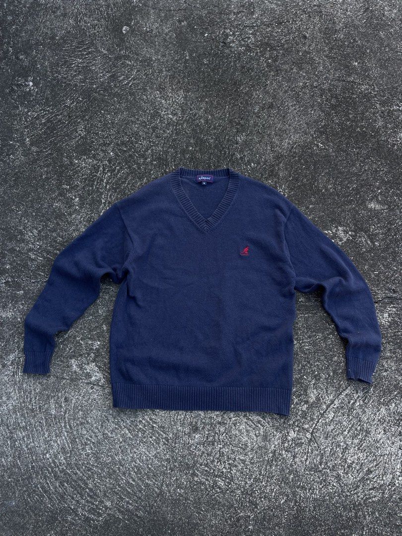 Kangol Navy Blue V-Neck Knit Sweater Size M (Category: Coats, Jackets and Outerwear) located in Tarlac. Submitted by supremo.0 (Listing ID 1470747149, Image 1). Description: - Brand: Vintage Knitted Kangol - Color: Navy blue - Size: Medium (tag on collar) (21x26) - Style: V-neck sweater with ribbed collar, cuffs, and hem - Details: Red embroidered kangaroo logo on left chest, small blue woven label near bottom hem - Authenticity: Interior license