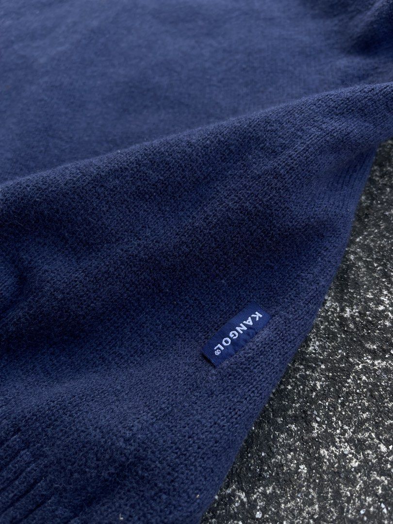 Kangol Navy Blue V-Neck Knit Sweater Size M (Category: Coats, Jackets and Outerwear) located in Tarlac. Submitted by supremo.0 (Listing ID 1470747149, Image 3). Description: - Brand: Vintage Knitted Kangol - Color: Navy blue - Size: Medium (tag on collar) (21x26) - Style: V-neck sweater with ribbed collar, cuffs, and hem - Details: Red embroidered kangaroo logo on left chest, small blue woven label near bottom hem - Authenticity: Interior license