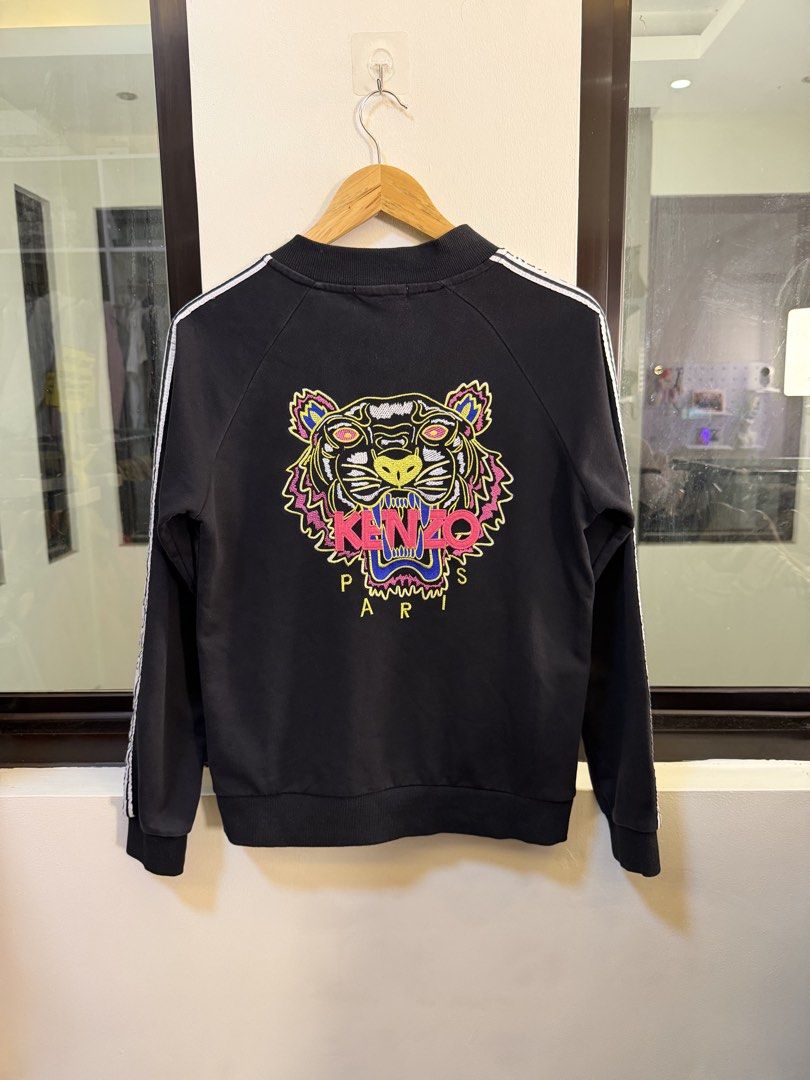 Kenzo Paris Full-Zip Track Jacket (Category: Coats, Jackets and Outerwear) located in Paranaque City. Submitted by preluxeshop_ph (Listing ID 1470802143, Image 3). Description: Brand: Kenzo Paris -Style: Full-Zip Track Jacket / Zip-Up Sweatshirt -Color: Black with white contrast taped logo trim along sleeves -Design Features: Large iconic Kenzo Tiger Head embroidery across the back, smaller embroidered -Tiger Head logo on the left chest, branded 