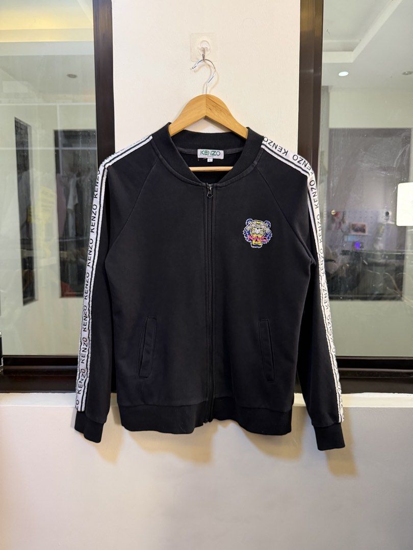 Kenzo Paris Full-Zip Track Jacket (Category: Coats, Jackets and Outerwear) located in Paranaque City. Submitted by preluxeshop_ph (Listing ID 1470802143, Image 2). Description: Brand: Kenzo Paris -Style: Full-Zip Track Jacket / Zip-Up Sweatshirt -Color: Black with white contrast taped logo trim along sleeves -Design Features: Large iconic Kenzo Tiger Head embroidery across the back, smaller embroidered -Tiger Head logo on the left chest, branded 