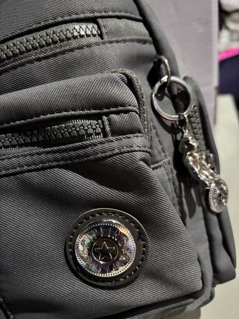 Kipling Grey Crossbody Bag with Multiple Zipper Pockets (Category: Cross-body Bags) located in Rizal. Submitted by va_nes_sa_ (Listing ID 1470818428, Image 3). Description: - Color: Grey - Material: Durable nylon - Strap: Adjustable with metal buckle detail - Pockets: Multiple front zip compartments, back exterior zip pocket, and inner storage pockets - Design: Pleated front panel with round metallic zipper pulls and logo badge - Condition: Clean