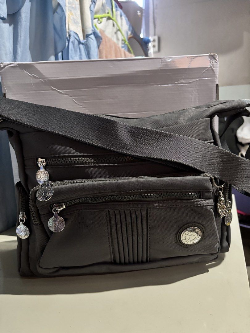 Kipling Grey Crossbody Bag with Multiple Zipper Pockets (Category: Cross-body Bags) located in Rizal. Submitted by va_nes_sa_ (Listing ID 1470818428, Image 1). Description: - Color: Grey - Material: Durable nylon - Strap: Adjustable with metal buckle detail - Pockets: Multiple front zip compartments, back exterior zip pocket, and inner storage pockets - Design: Pleated front panel with round metallic zipper pulls and logo badge - Condition: Clean