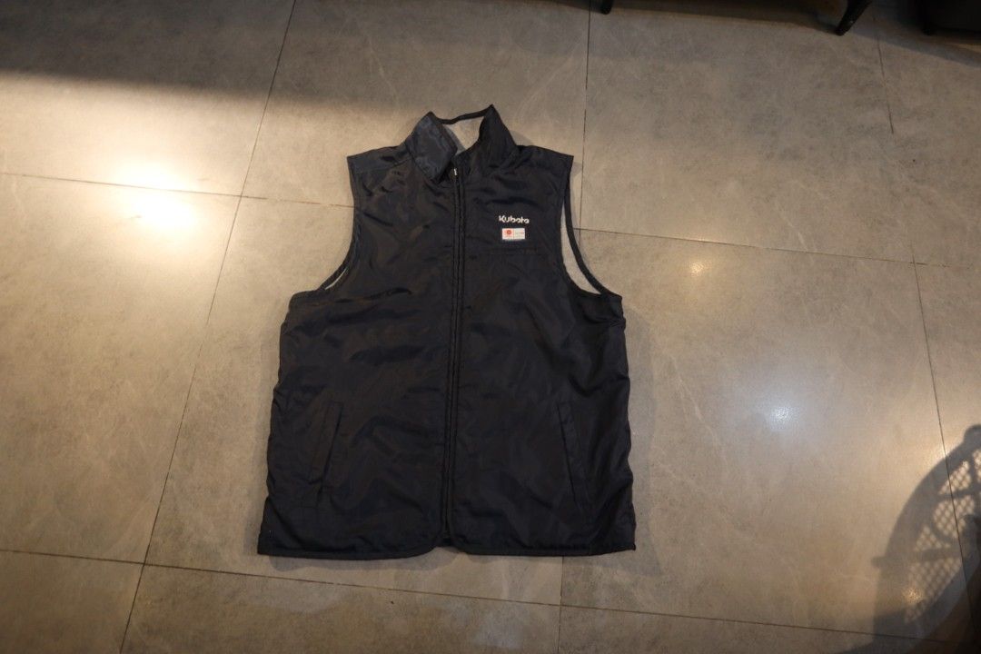 Kubota Branded Navy Blue Vest (Category: Vests) located in Manila. Submitted by krzxyprk (Listing ID 1470771291, Image 1). Description: - Color: Dark navy blue - Features: Full zip front, two side pockets, and a stand-up collar - Branding: Small white Kubota logo with a red square badge on the chest - Condition: Clean, zipper works smoothly - Ideal for: Chilly days, working outdoors, or around the yard.