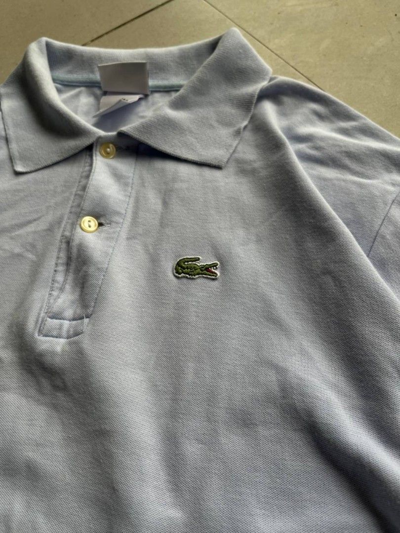 Lacoste Light Blue Polo Shirt Size 7 (Category: Tshirts & Polo Shirts ) located in Santa Cruz. Submitted by remsonnnc (Listing ID 1470814389, Image 2). Description: - Brand: Lacoste - Color: Light blue - Size: 7 - Material: 100% cotton pique fabric (Designed in France, made in Peru) - Details: Classic 2-button placket with mother-of-pearl buttons, standard collar, short sleeves - Logo: Iconic embroidered green crocodile on the chest - Condition: 