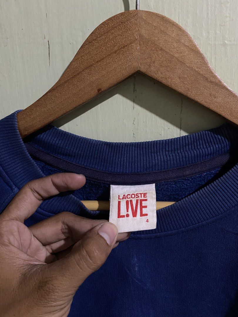 Lacoste Live Blue Sweatshirt Size 4 (Category: Coats, Jackets and Outerwear) located in Pandi. Submitted by nasya_thrift_collection2023 (Listing ID 1470858022, Image 2). Description: - Brand: Lacoste Live - Item: Crewneck Sweatshirt with side stripes - Color: Blue with dark blue contrast side stripes - Logo: Classic embroidered green crocodile on chest - Size: 4 (US Medium / 105) - Material: 83% cotton, 17% polyester blend - Details: Ribbed colla