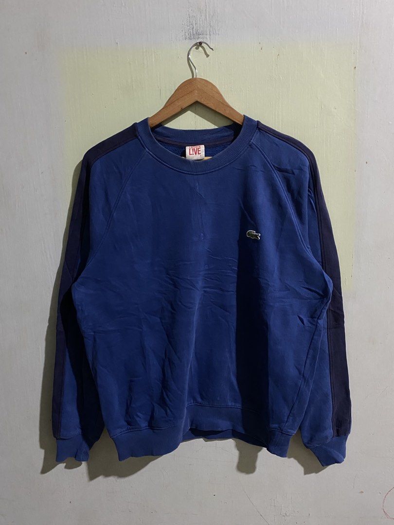 Lacoste Live Blue Sweatshirt Size 4 (Category: Coats, Jackets and Outerwear) located in Pandi. Submitted by nasya_thrift_collection2023 (Listing ID 1470858022, Image 1). Description: - Brand: Lacoste Live - Item: Crewneck Sweatshirt with side stripes - Color: Blue with dark blue contrast side stripes - Logo: Classic embroidered green crocodile on chest - Size: 4 (US Medium / 105) - Material: 83% cotton, 17% polyester blend - Details: Ribbed colla