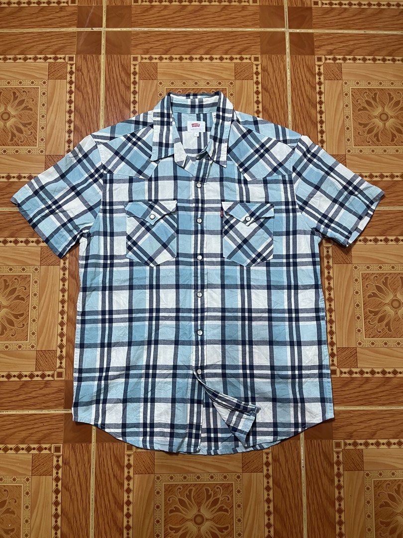 Levi's Blue Plaid Short Sleeve Button-Up Shirt (Category: Activewear) located in Kidapawan. Submitted by azythrift (Listing ID 1470824329, Image 1). Description: - Brand: Levi's - Style: Short sleeve button-up shirt - Pattern: Blue, white, and navy plaid - Details: Pearl snap front closure, two chest pockets with snaps, iconic Levi's red tab - Size: Medium.