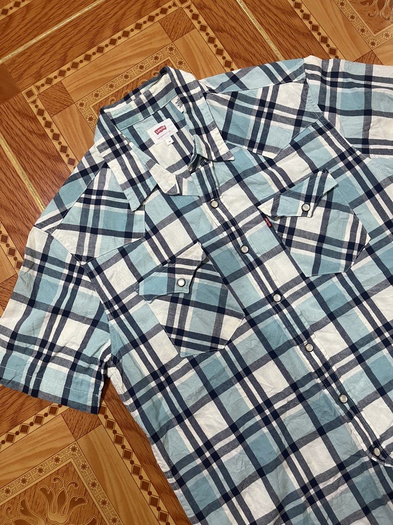 Levi's Blue Plaid Short Sleeve Button-Up Shirt (Category: Activewear) located in Kidapawan. Submitted by azythrift (Listing ID 1470824329, Image 3). Description: - Brand: Levi's - Style: Short sleeve button-up shirt - Pattern: Blue, white, and navy plaid - Details: Pearl snap front closure, two chest pockets with snaps, iconic Levi's red tab - Size: Medium.