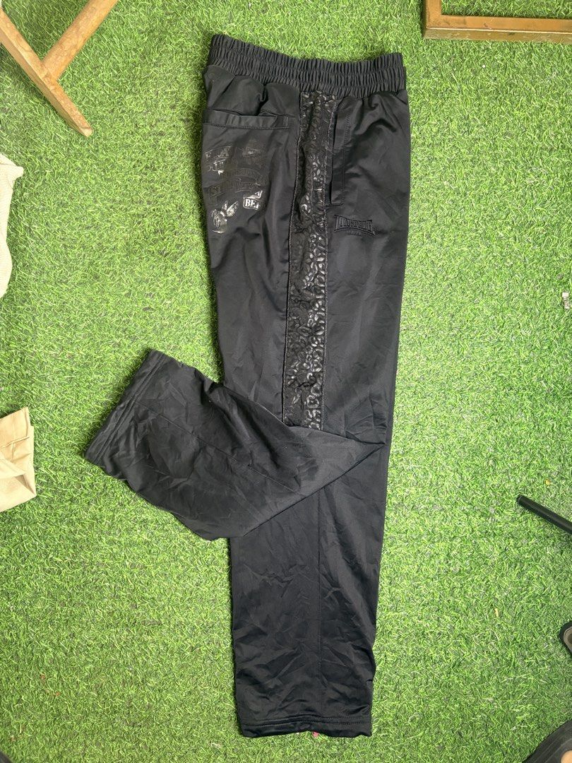 Lionsdale track Pant (Category: Trousers) located in Manila. Submitted by josh2295 (Listing ID 1470765447, Image 2). Description: black Lonsdale track pants featuring an elastic waistband, side pockets, and a patterned or textured side stripe/panel with the Lonsdale logo embroidery W:30-38 L:40 LH:8.