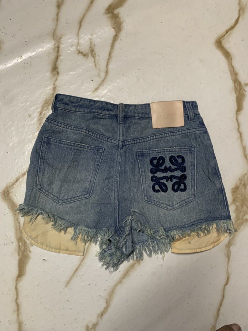 Loewe Anagram Denim Shorts Size 38 (Category: Luxury Apparel) located in Iloilo. Submitted by johnpullan30303 (Listing ID 1470833448, Image 1). Description: - Brand: Loewe - Item: Denim shorts in light wash - Size: 38 - Material: 100% cotton (Made in Italy) - Details: Iconic Anagram logo embroidered on the back pocket - Hem: Raw frayed hems with pocket lining visible underneath - Branding: Tan leather patch with embossed Loewe logo at the back wa