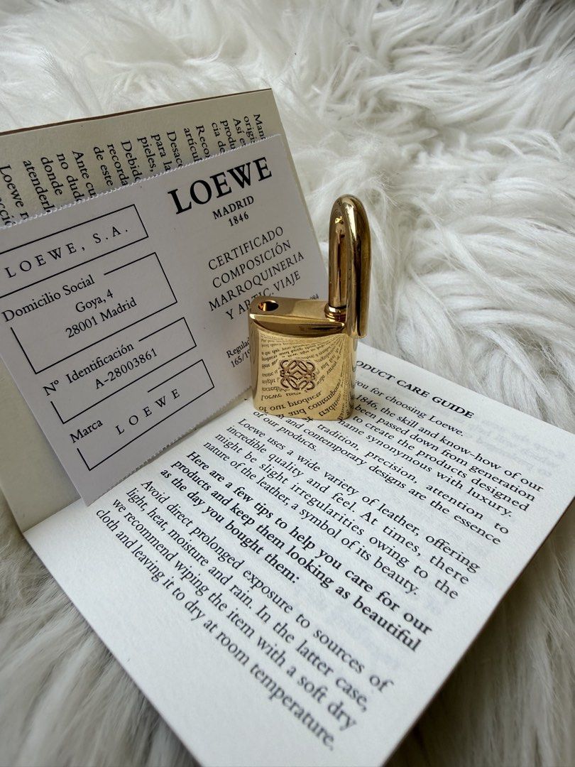 Loewe Madrid 1846 Gold Padlock (Category: Luxury Bags & Wallets) located in Solano. Submitted by hayami. (Listing ID 1470793837, Image 3). Description: - Authentic Loewe gold-tone padlock with engraved branding and Anagram logo - Heavy, solid metal design with a fully functional shackle - Clean, polished finish suitable for collectors or as a replacement bag lock - Includes original Loewe Madrid 1846 certificate card, product care guide, and pape