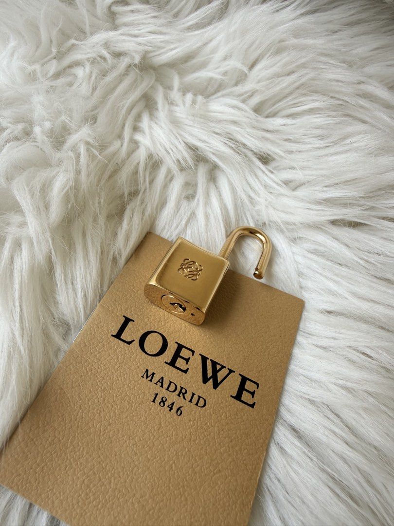 Loewe Madrid 1846 Gold Padlock (Category: Luxury Bags & Wallets) located in Solano. Submitted by hayami. (Listing ID 1470793837, Image 1). Description: - Authentic Loewe gold-tone padlock with engraved branding and Anagram logo - Heavy, solid metal design with a fully functional shackle - Clean, polished finish suitable for collectors or as a replacement bag lock - Includes original Loewe Madrid 1846 certificate card, product care guide, and pape