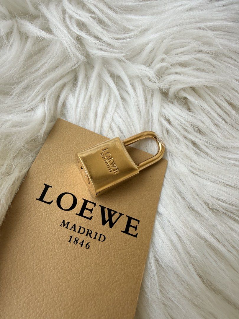 Loewe Madrid 1846 Gold Padlock (Category: Luxury Bags & Wallets) located in Solano. Submitted by hayami. (Listing ID 1470793837, Image 2). Description: - Authentic Loewe gold-tone padlock with engraved branding and Anagram logo - Heavy, solid metal design with a fully functional shackle - Clean, polished finish suitable for collectors or as a replacement bag lock - Includes original Loewe Madrid 1846 certificate card, product care guide, and pape