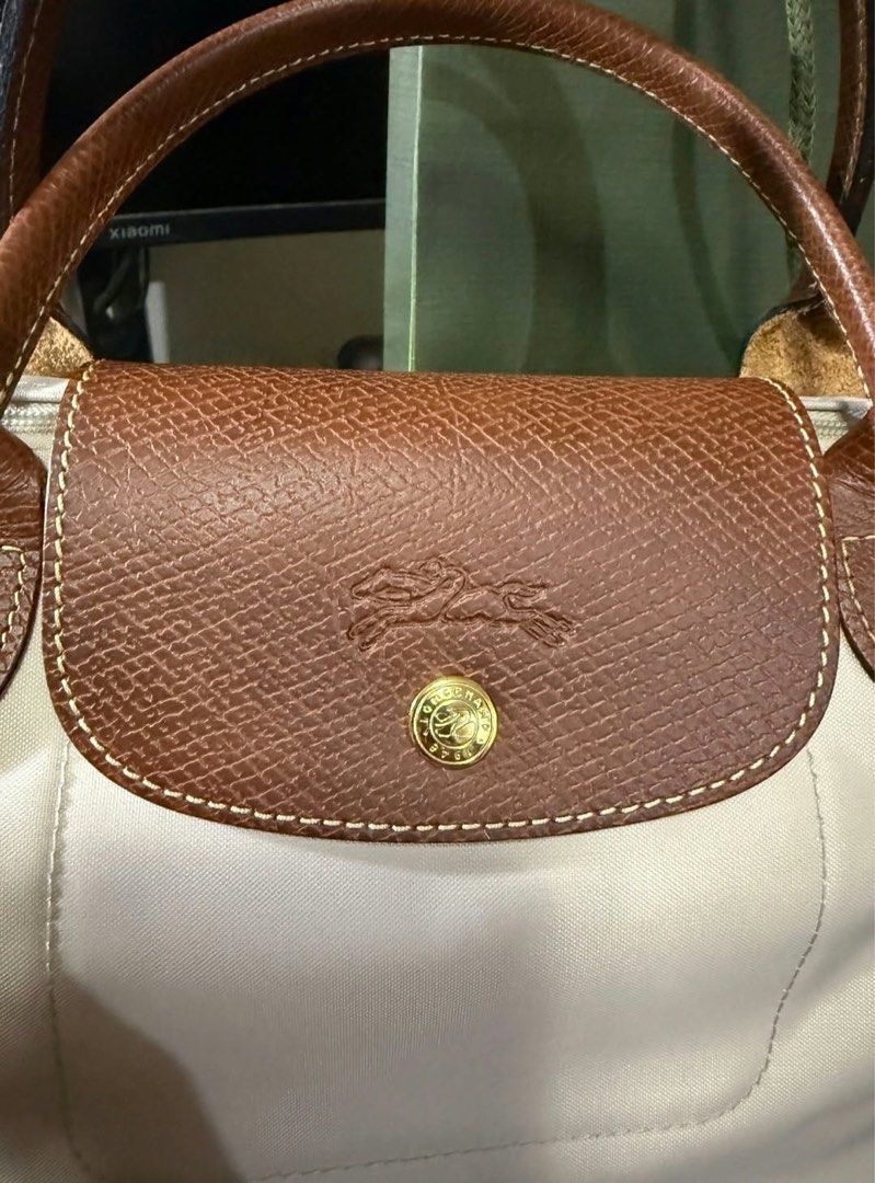 Longchamp Le Pliage Handbag Beige Brown (Category: Luxury Bags & Wallets) located in Manila. Submitted by 123cheesedog (Listing ID 1470757793, Image 2). Description: - Brand: Longchamp Le Pliage Bought from RUSTANS - Condition: Brand new, unused, and still wrapped in protective paper - Color: Elegant beige nylon body with rich brown leather handle and flap - Hardware: Classic gold-tone hardware with signature horse logo zipper pull - Style: Timel