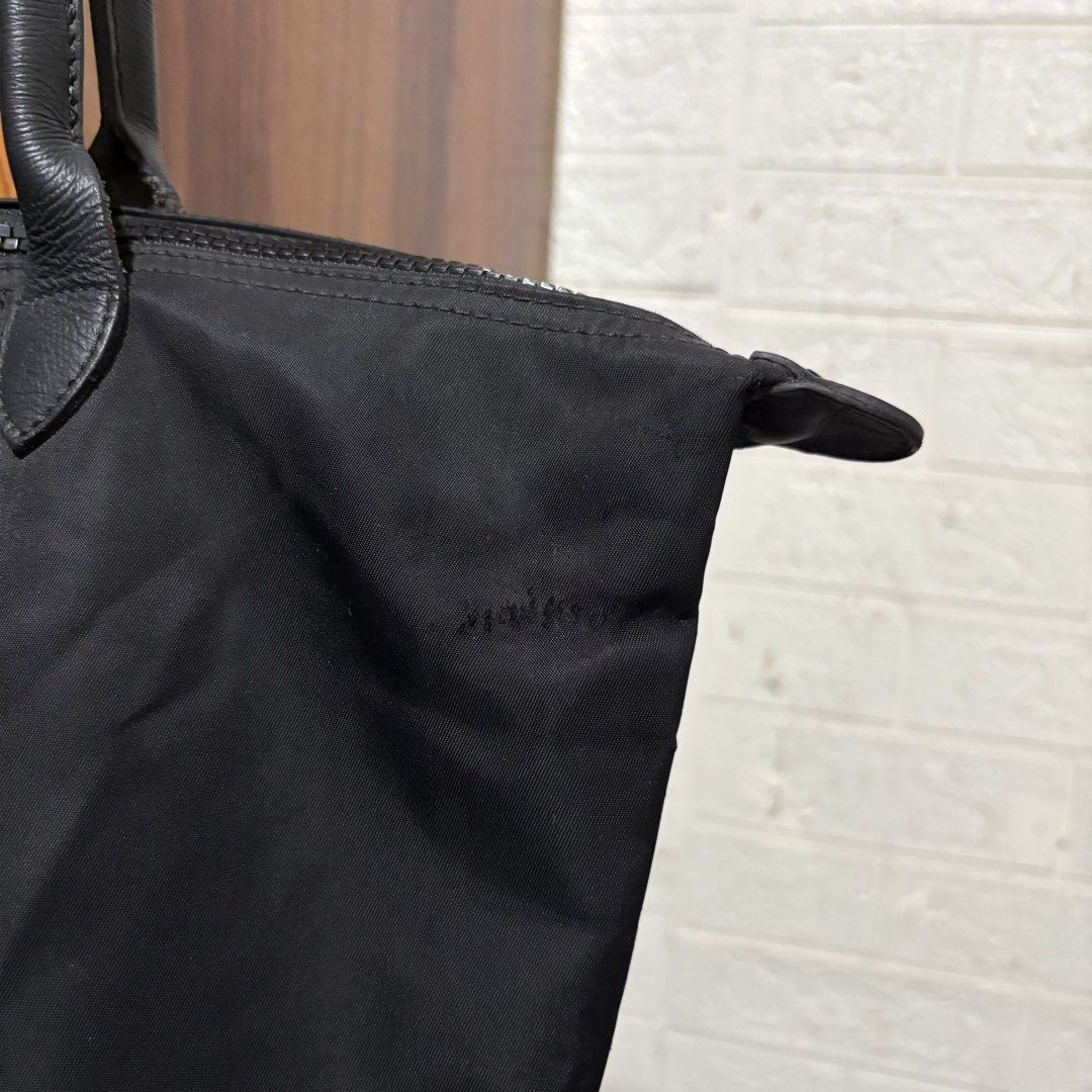 Longchamp Le Pliage Nylon Tote Bag Black (Category: Tote Bags) located in Carmen. Submitted by rr_thrifts (Listing ID 1470767191, Image 2). Description: Longchamp Le Pliage tote bag in classic black nylon with dark leather handles and flap. Zip top closure keeps things secure. Lightweight and folds up easily. Bottom corners show wear and tiny holes from regular use. Plenty of life left for daily commutes or travel..