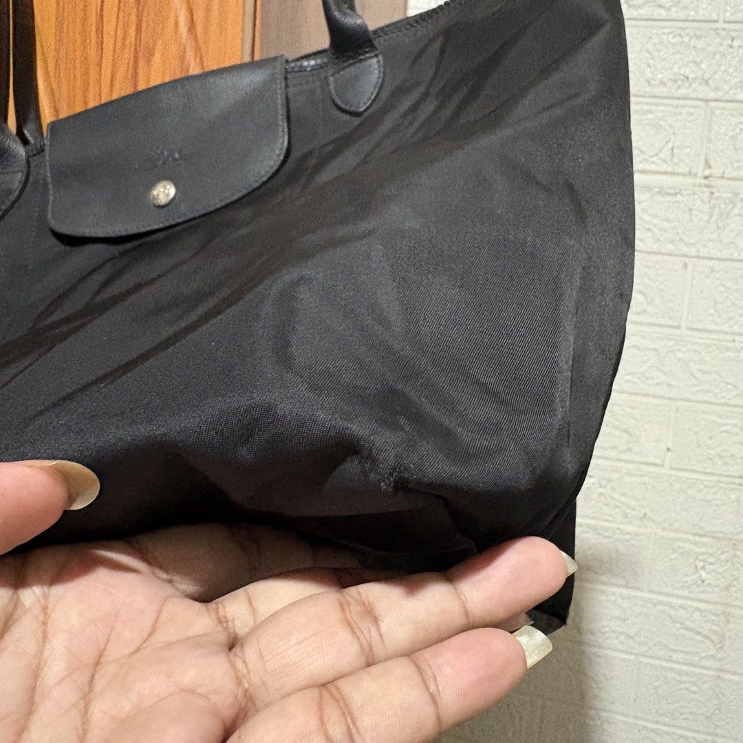 Longchamp Le Pliage Nylon Tote Bag Black (Category: Tote Bags) located in Carmen. Submitted by rr_thrifts (Listing ID 1470767191, Image 3). Description: Longchamp Le Pliage tote bag in classic black nylon with dark leather handles and flap. Zip top closure keeps things secure. Lightweight and folds up easily. Bottom corners show wear and tiny holes from regular use. Plenty of life left for daily commutes or travel..