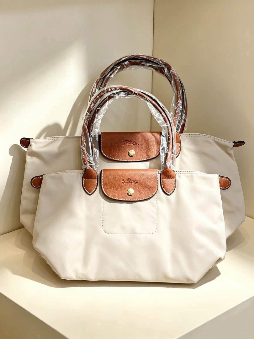 Longchamp Le Pliage Nylon Tote Bag Various Colors (Category: Tote Bags) located in Santo Domingo. Submitted by krizzies_korner (Listing ID 1470806786, Image 2). Description: - Brand new Longchamp Le Pliage nylon tote bags - Available colors: Black, Beige, Yellow, Orange, and Red - Iconic foldable design with brown leather top handles and flap snap closure - Elegant gold-tone hardware throughout - Handles still wrapped in original plastic packagin