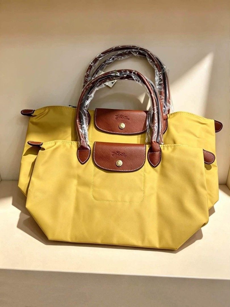 Longchamp Le Pliage Nylon Tote Bag Various Colors (Category: Tote Bags) located in Santo Domingo. Submitted by krizzies_korner (Listing ID 1470806786, Image 3). Description: - Brand new Longchamp Le Pliage nylon tote bags - Available colors: Black, Beige, Yellow, Orange, and Red - Iconic foldable design with brown leather top handles and flap snap closure - Elegant gold-tone hardware throughout - Handles still wrapped in original plastic packagin