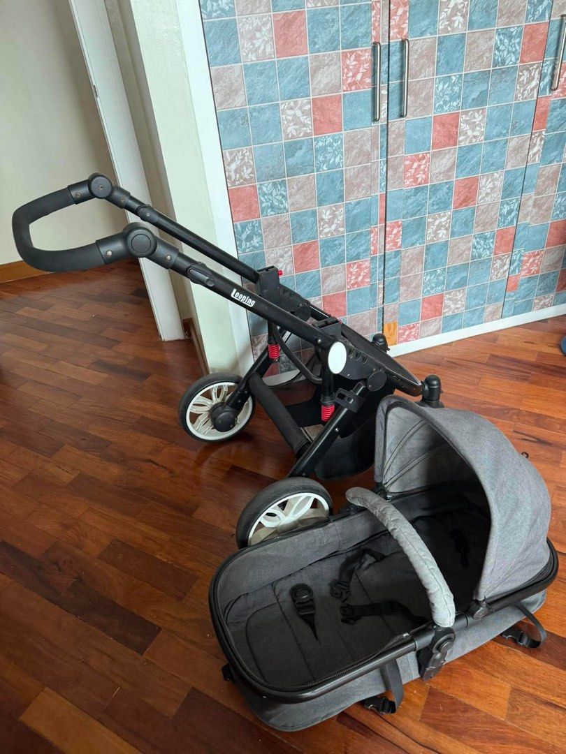 Looping Sydney stroller (Category: Strollers) located in Makati City. Submitted by akimoie (Listing ID 1470852210, Image 3). Description: - Color: Dark grey and black fabric - Wheels: Large wheels with white rims for smooth rides on rough pavement - Suspension: Visible red suspension springs for added comfort - Canopy: Large foldable canopy to block the sun - Storage: Spacious bottom basket for bags and gear - Handlebar: Comfortable foam-wrapped 
