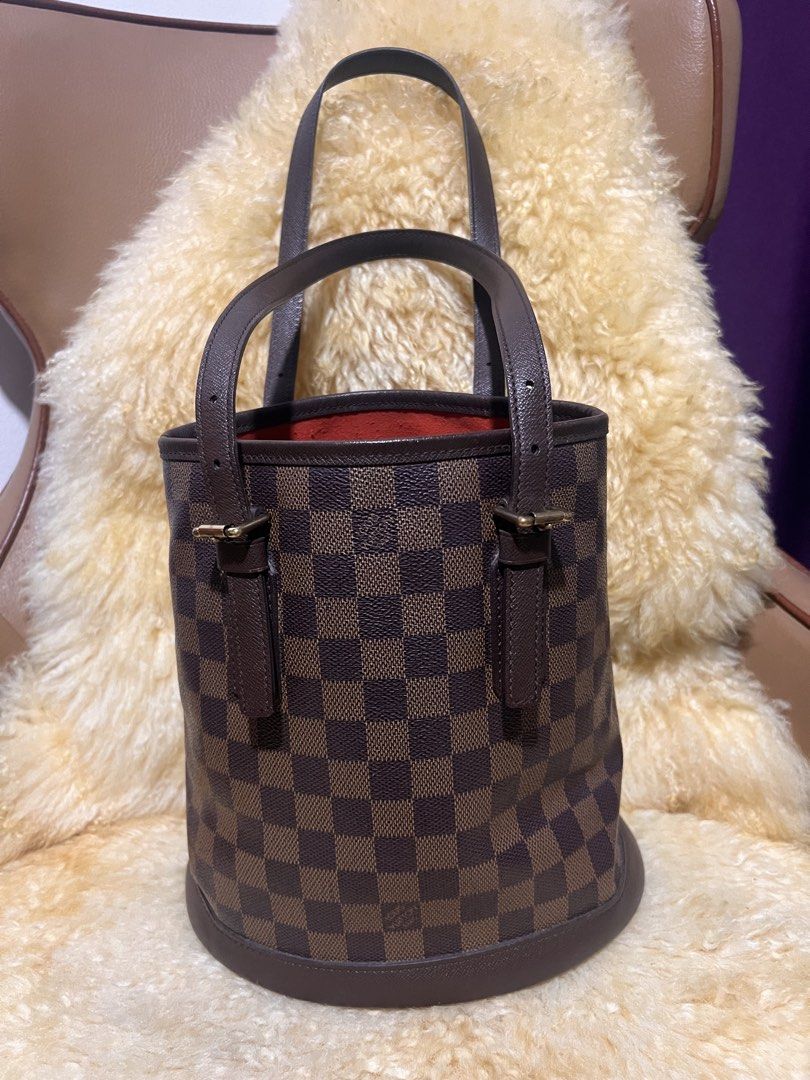 Louis Vuitton Damier Ebene Bucket Bag (Category: Luxury Bags & Wallets) located in Quezon City. Submitted by fly29 (Listing ID 1470856767, Image 1). Description: - Brand: Louis Vuitton - Style: Bucket bag in iconic Damier Ebene canvas - Trim & Straps: Dark brown leather with adjustable shoulder straps - Hardware: Gold-tone hardware with clean condition - Base: Flat oval base equipped with four protective feet - Interior: Vibrant red lining - Cond