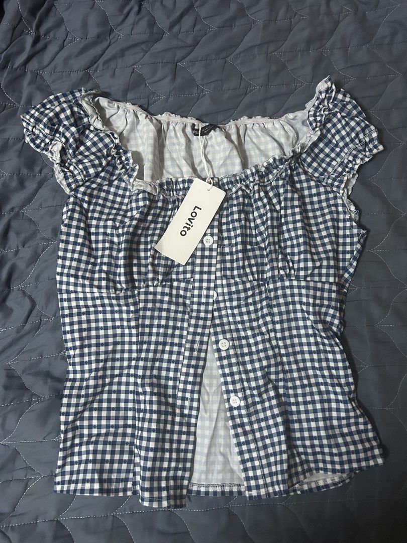 Lovito Blue White Gingham Checkered Off Shoulder Top (Category: Blouses) located in Manila. Submitted by ardol (Listing ID 1470781469, Image 1). Description: - size: s- semi med - Brand: Lovito - Condition: Brand new with original paper tag attached - Pattern: Blue and white gingham checkered - Design: Ruffled neckline (can be worn off-shoulder), short cap sleeves, and front button placket - Fit: Smocked elastic at neck and bust for a comfortable