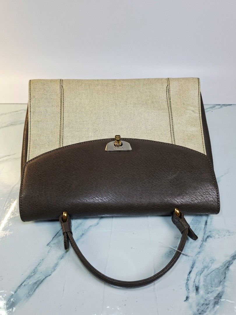 Lydia Two-Tone Leather and Canvas Handbag (Category: Purses & Pouches) located in Pasay City. Submitted by onick_79 (Listing ID 1470918131, Image 3). Description: - Brand: Pelle Borsa -Dimensions: L29 x H23 x W11 cm - Design: Structured shape with a brown textured leather flap and light beige perforated canvas body - Hardware: Silver and gold-tone metal closure engraved with the Lydia brand name - Handle: Single top handle attached with elegant g
