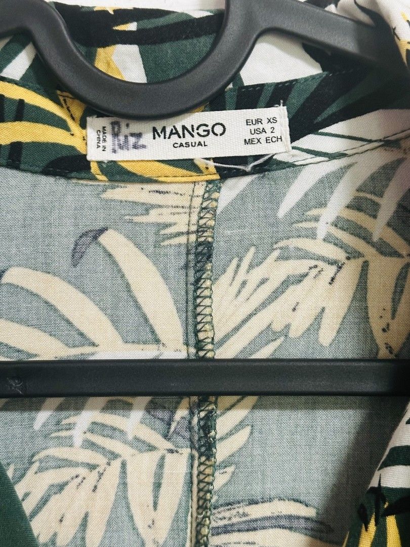 Mango Casual Tropical Leaf Print Button Up Shirt (Category: Shirts) located in Manila. Submitted by thebestre (Listing ID 1470878854, Image 2). Description: - Brand: Mango - Style: Casual button-down with camp collar and tortoiseshell buttons - Print: Bold green, yellow, and white tropical palm leaf pattern - Fit & Size: Relaxed fit, EUR XS / USA 2 - Material: Lightweight fabric, ideal for warm weather and vacations - Condition: Excellent pre-lov