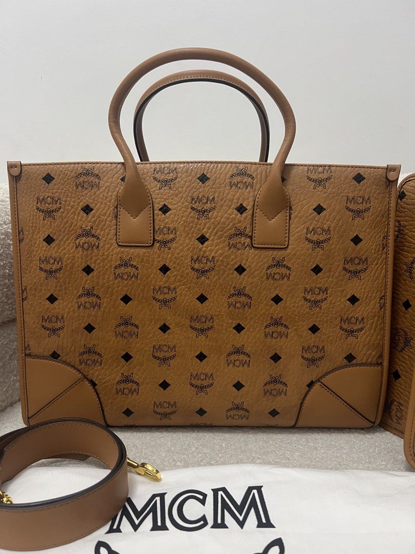 MCM Cognac Visetos Monogram Tote Bag with Pouch (Category: Tote Bags) located in Abulug. Submitted by jamiecammie (Listing ID 1470820909, Image 2). Description: - Authentic MCM structured tote bag in classic cognac Visetos monogram - Crafted with durable pebble-textured leather and dark brown trim - Includes dual top handles and a detachable, adjustable shoulder strap - Comes with a matching wallet/pouch and the original dust bag - Features premi