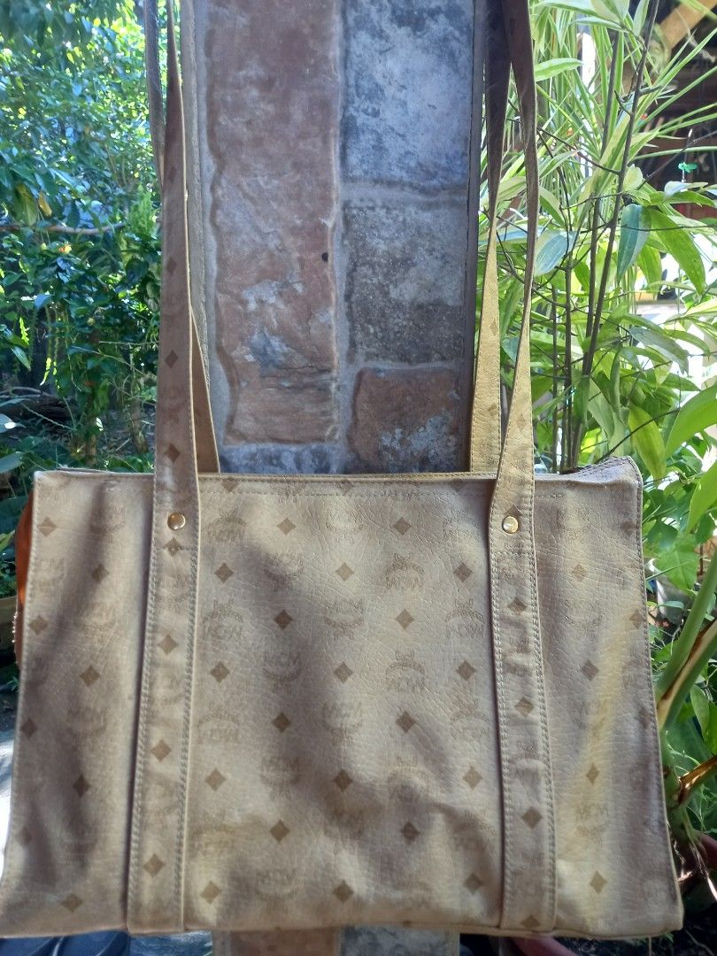 MCM Monogram Tote Bag Beige Gold (Category: Luxury Bags & Wallets) located in Davao. Submitted by kirk214red-50020 (Listing ID 1470795724, Image 2). Description: - Brand: MCM - Style: Classic shoulder tote bag - Color: Light beige with signature monogram print - Material: Leather - Hardware: Gold-tone brass plaque stamped with MCM München and serial number U5297 - Features: Dual long shoulder straps with branded studs, external front pocket - Cap