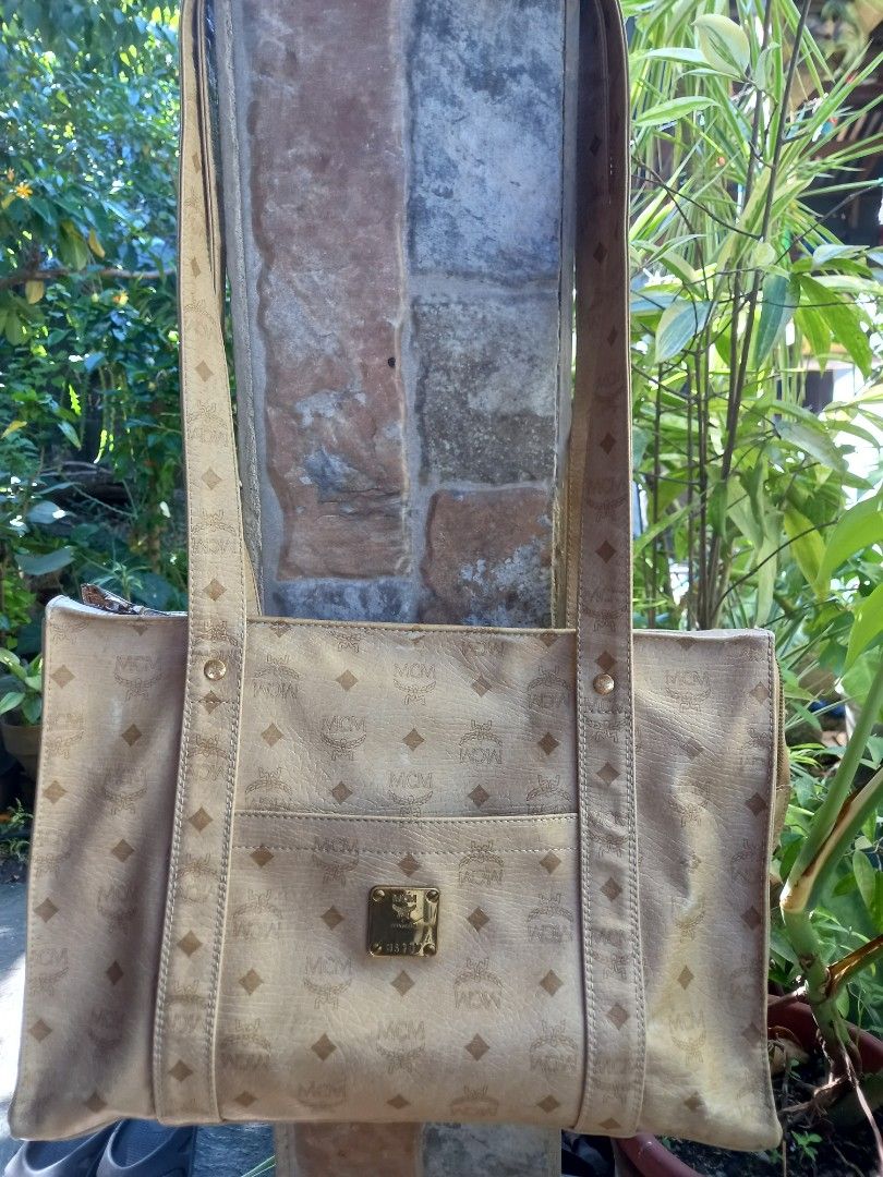 MCM Monogram Tote Bag Beige Gold (Category: Luxury Bags & Wallets) located in Davao. Submitted by kirk214red-50020 (Listing ID 1470795724, Image 1). Description: - Brand: MCM - Style: Classic shoulder tote bag - Color: Light beige with signature monogram print - Material: Leather - Hardware: Gold-tone brass plaque stamped with MCM München and serial number U5297 - Features: Dual long shoulder straps with branded studs, external front pocket - Cap