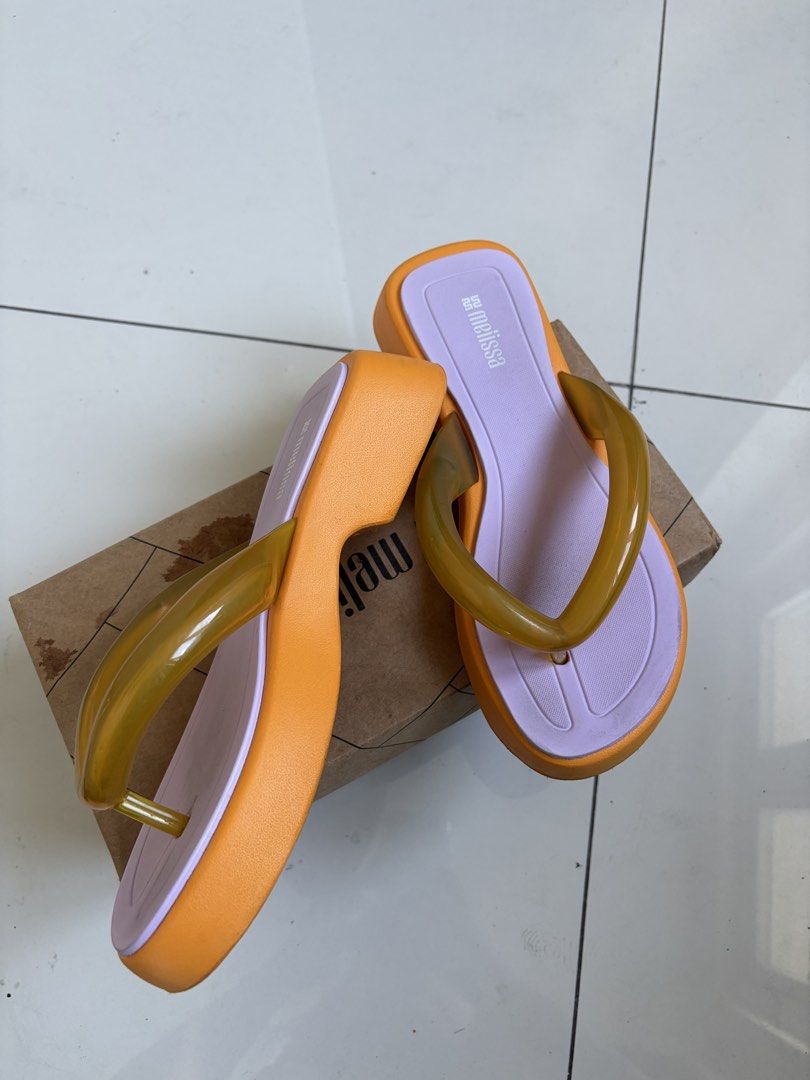 Melissa Platform Flip Flops Orange Purple Size 38 (Category: Slippers and slides) located in Manila. Submitted by kylicee (Listing ID 1470898437, Image 2). Description: - Brand: Melissa - Style: Platform flip flops - Color: Vibrant orange, soft purple, and translucent amber strap detail - Size: EUR 38 / US 7 / BRA 36 - Features: Chunky platform sole with unique patterned outsole - Inclusion: Original shoe box included - Condition: Excellent / Rea
