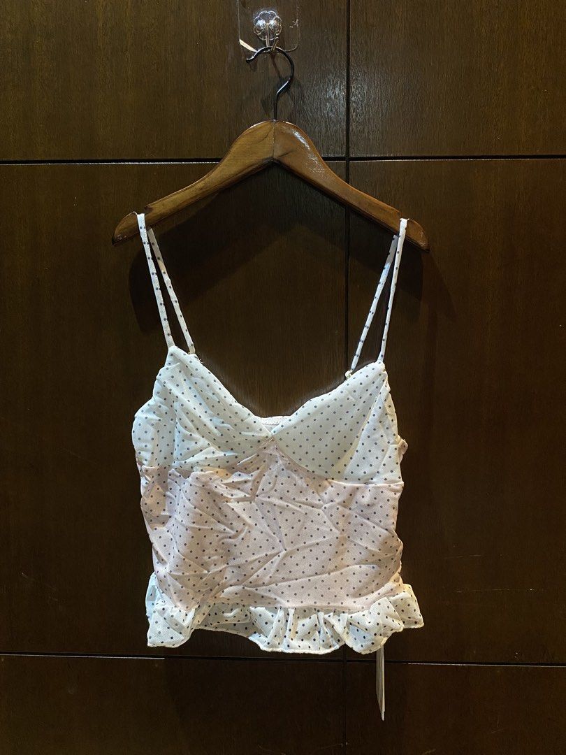 Mesh Polka Dot Cami Top With Ruffle Hem (Category: Sleeveless) located in Manila. Submitted by bina_meia (Listing ID 1470831826, Image 2). Description: - Color/Pattern: White and pink mesh with black polka dots - Design: V-neckline, adjustable thin straps, ruched body, and ruffled hem - Condition: Brand new with original tags attached - Styling: Perfect for casual outings or layering.