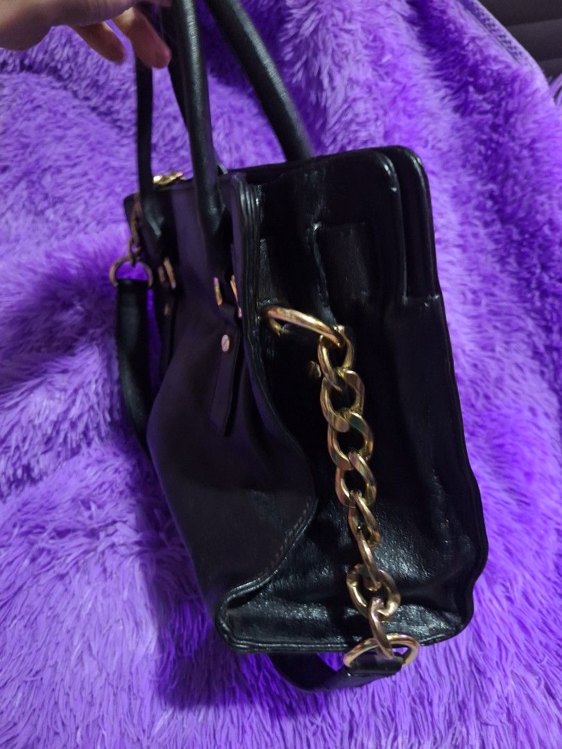 Michael Kors Black Hamilton Handbag With Gold Hardware (Category: Luxury Bags & Wallets) located in Quezon City. Submitted by cloudymay (Listing ID 1470820362, Image 2). Description: Black Michael Kors satchel bag. Gold lock detail on the front, plus a chunky gold chain strap on the side. Double top handles. Tan fabric lining inside with zipper pockets. Structured shape with pebbled texture. Zip closure on top. Min signs of wear on leather: folds