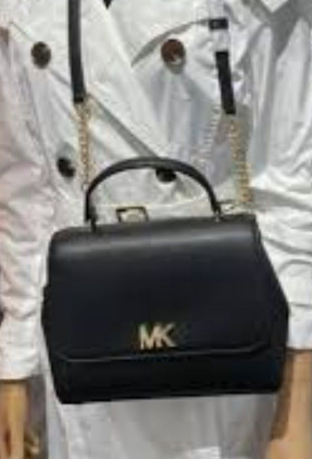 Michael Kors Black Leather Handbag with Gold Hardware (Category: Cross-body Bags) located in Manila. Submitted by lene48 (Listing ID 1470853295, Image 2). Description: Black leather Michael Kors handbag with prominent gold MK logo on the front flap. Structured top handle design paired with a chain-accented shoulder strap. Interior lined in black branded fabric featuring zippered pockets and a slip pocket. Gold tone protective feet on the base. Mi