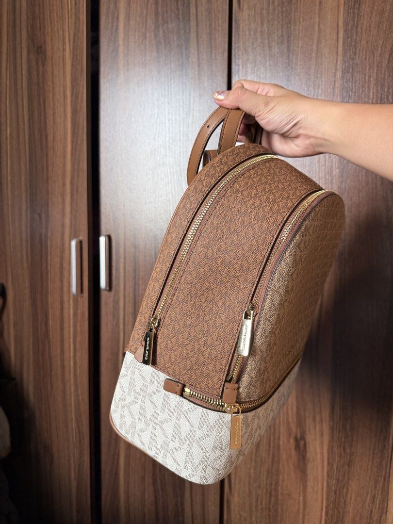 Michael Kors Brown White Monogram Backpack Bag (Category: Backpacks) located in Manila. Submitted by REI.PH (Listing ID 1470755896, Image 1). Description: - Authentic Michael Kors signature monogram backpack - Color/Material: Brown and white coated canvas with tan leather straps - Hardware: Gold-tone hardware with secure zip closure - Interior: Spacious with clean fabric lining - Exterior: Handy front zip pocket for easy access - Condition: Immac