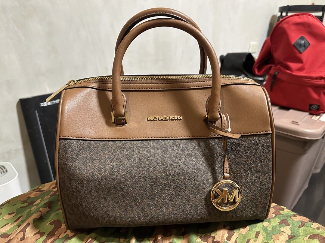 Michael Kors Medium Duffle Satchel Bag (Category: Luxury Bags & Wallets) located in Valenzuela. Submitted by nicadahhh (Listing ID 1470906244, Image 1). Description: MICHAEL KORS - Brown monogram with brown leather trim - Hardware: Gold-tone with hanging MK charm - Closure: Secure zip-top - Condition Note: Minor peeling and wear near the handle attachment point (highlighted in close-up photo); interior and structure are in great shape - no strap 