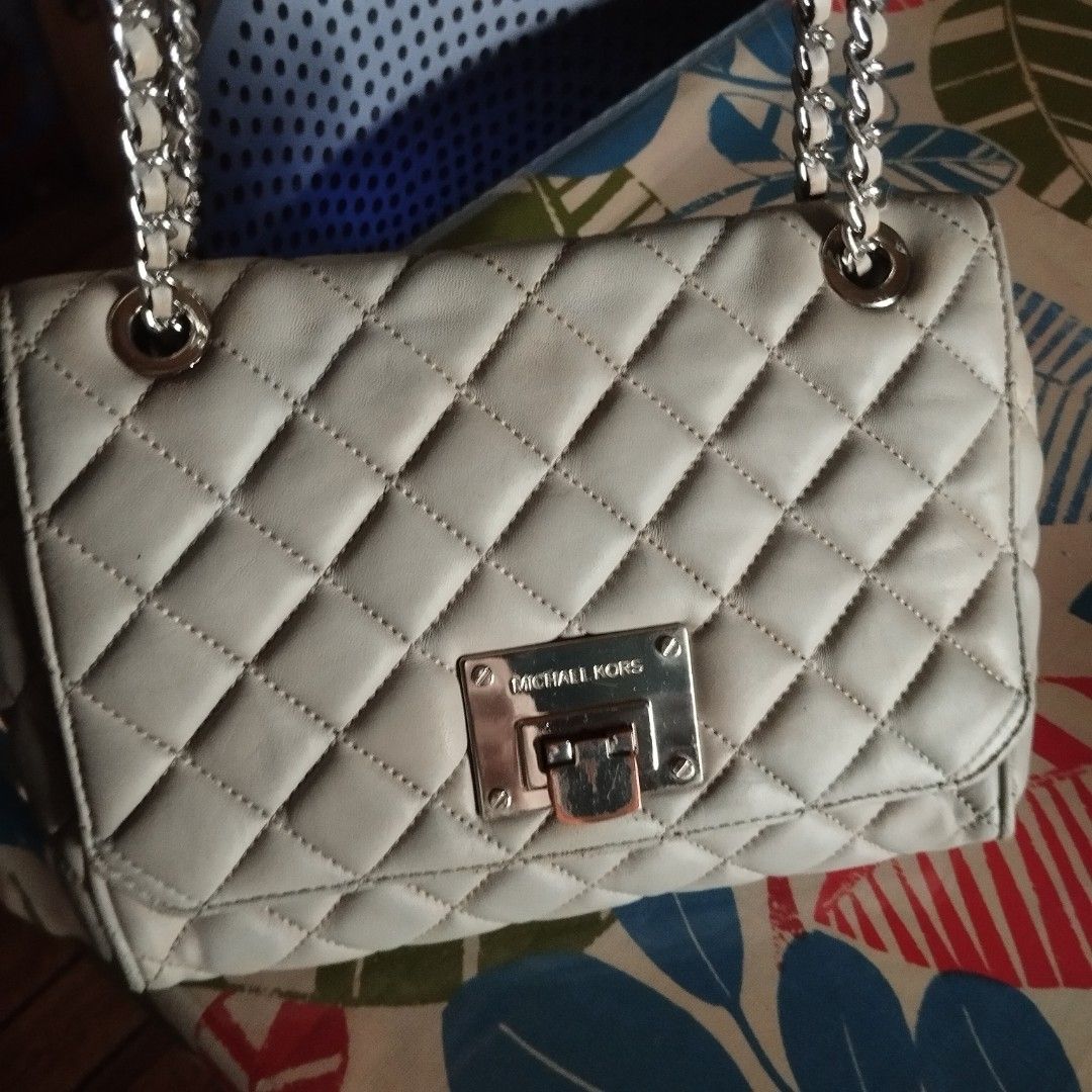 Michael Kors Quilted Leather Shoulder Bag (Category: Cross-body Bags) located in Manila. Submitted by lene48 (Listing ID 1470776101, Image 1). Description: Michael Kors quilted leather shoulder bag in a neutral grey shade. Silver-tone chain strap interwoven with leather. Front metal turn-lock closure with engraved logo. Quilted diamond pattern across the body. Interior lined with MK monogram fabric, including an embossed leather brand patch. Show