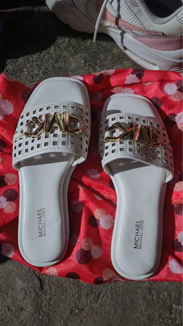 Michael Kors White Sandals Size 6M (Category: Flats & Sandals) located in Baguio. Submitted by markmartin3 (Listing ID 1470886215, Image 1). Description: - Brand: Michael Kors - Style: White slip-on sandals / flat style - Size: 6M - Details: Cutout grid strap design with signature gold-tone logo hardware - Soles: White inner sole with stamped branding, brown outer sole with textured grip and embossed MK logo circle - Condition: Clean finish, perf