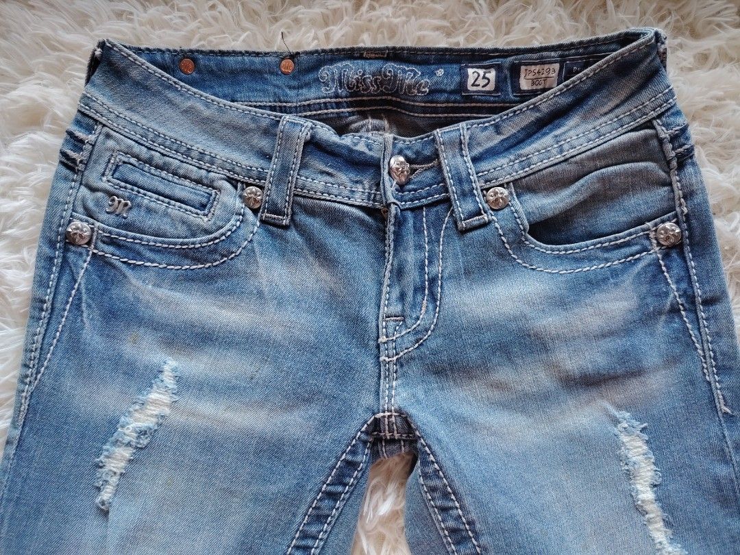 Miss Me Boot Cut Jeans Size 25 JP5429B (Category: Jeans) located in Caba. Submitted by valerie_18947 (Listing ID 1470776614, Image 3). Description: - Brand/Model: Miss Me Boot Cut Jeans (Style JP5429B) - Size: 25 - Wash: Light blue with front knee distressing and frayed edges - Details: Eye-catching embroidered back pockets with rhinestone, sequin, and hardware rivet accents - Fit/Rise: Mid-rise with signature white contrast stitching - Material: