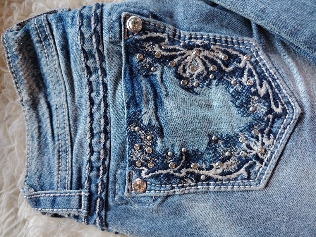 Miss Me Boot Cut Jeans Size 25 JP5429B (Category: Jeans) located in Caba. Submitted by valerie_18947 (Listing ID 1470776614, Image 2). Description: - Brand/Model: Miss Me Boot Cut Jeans (Style JP5429B) - Size: 25 - Wash: Light blue with front knee distressing and frayed edges - Details: Eye-catching embroidered back pockets with rhinestone, sequin, and hardware rivet accents - Fit/Rise: Mid-rise with signature white contrast stitching - Material: